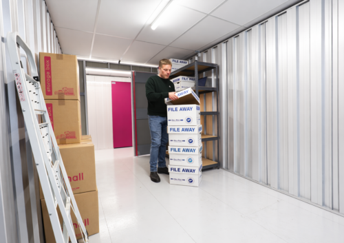 Man moving boxes inside a self storage unit at The Store Room